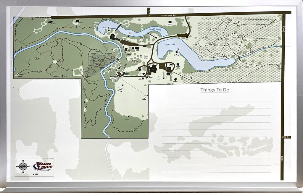 A framed site map whiteboard showing trails, lakes, buildings, and a blank Things To Do area on the right.